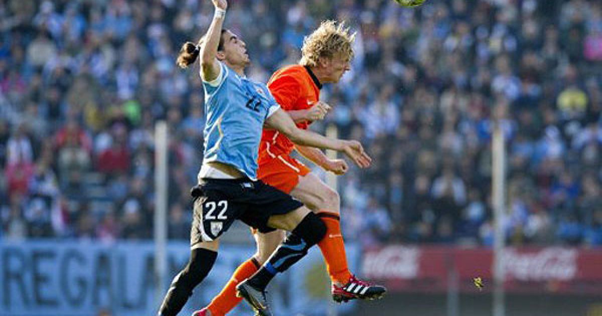 Уругвай, Монтевідео. Голландський футболіст Дірк Куйт веде боротьбу за м'яч з гравцем Уругваю Мартіном Касересом під час футбольного матчу Уругвай-Нідерланди на стадіоні Estadio Centenario в Монтевідео. / © AFP