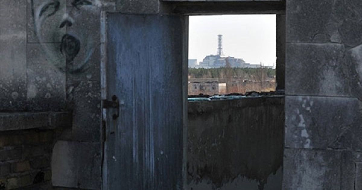 Україна, Чорнобиль. Вид на 4-ий енергоблок Чорнобильської АЕС з даху будинку в місті- привиді Прип&#039;ять. Українські фахівці регулярно здійснюють перевірки рівня радіації та цілісності бетонного укриття зруйнованого реактора, який вибухнув 26 квітня 1986 року. / © AFP