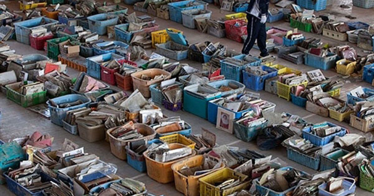 Японія, Наторі. Чоловік шукає свої фотографії серед речей, які були зібрані добровольцями у смітті та уламках будинків в місті Наторі, префектура Міягі. / © AFP