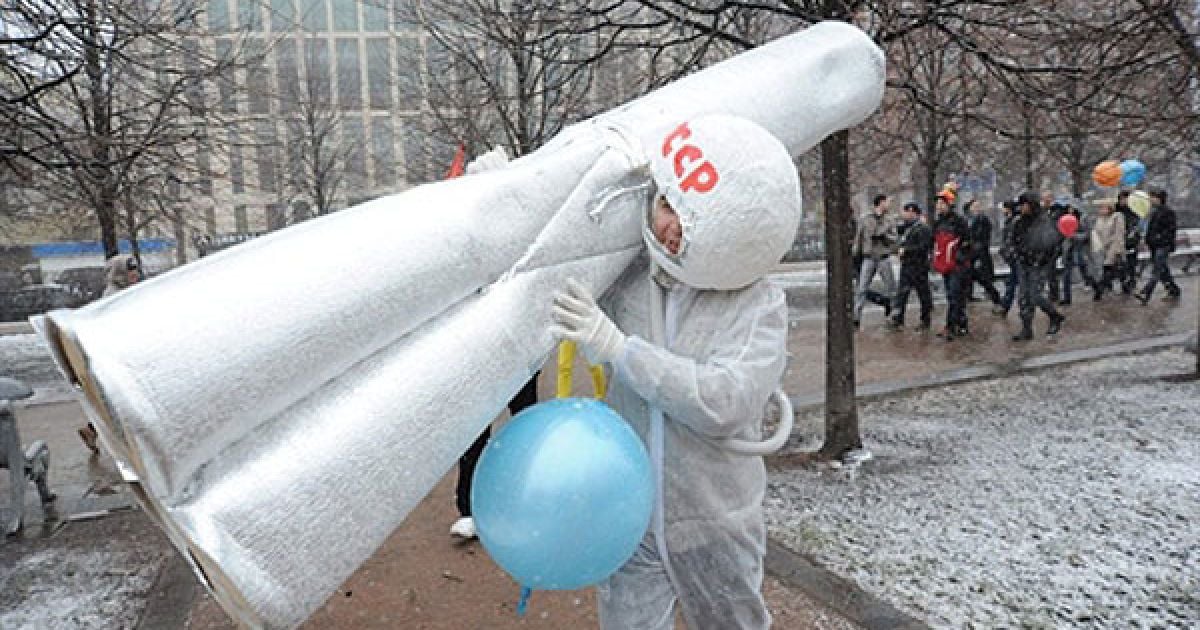 Росія, Москва. Молода людина у костюмі, що імітує космічний скафандр, несе макет космічного корабля радянського космонавта Юрія Гагаріна під час акції, присвяченої 50-річному ювілею першого польоту людини в космос. / © AFP