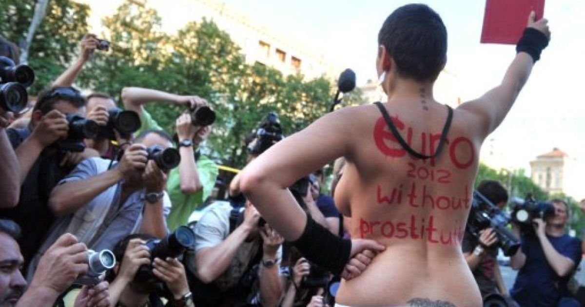 Україна. Київ. Активістка жіночого руху FEMEN показує червону картку під час топлес-протесту "Євро-2012 без проституції" в Києві. В Києві стартував годинник зворотнього відліку часу до початку чемпіонату Євро-2012. / © AFP