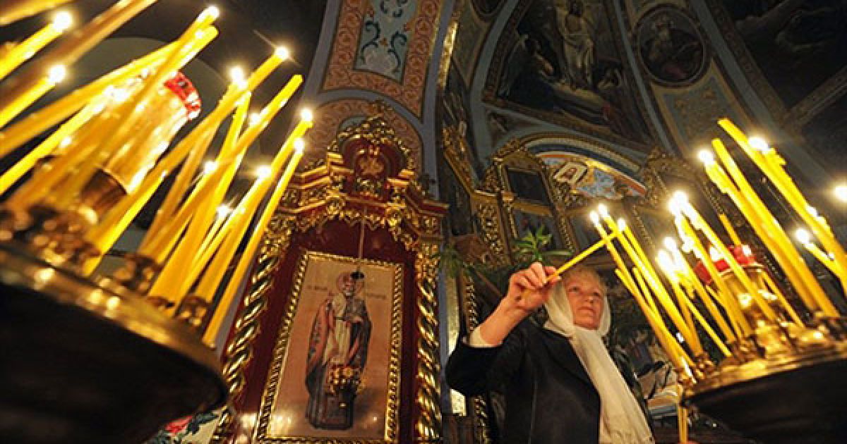 Україна, Чорнобиль. Жінка запалює свічку під час православного пасхального богослужіння в місті Чорнобиль. / © AFP