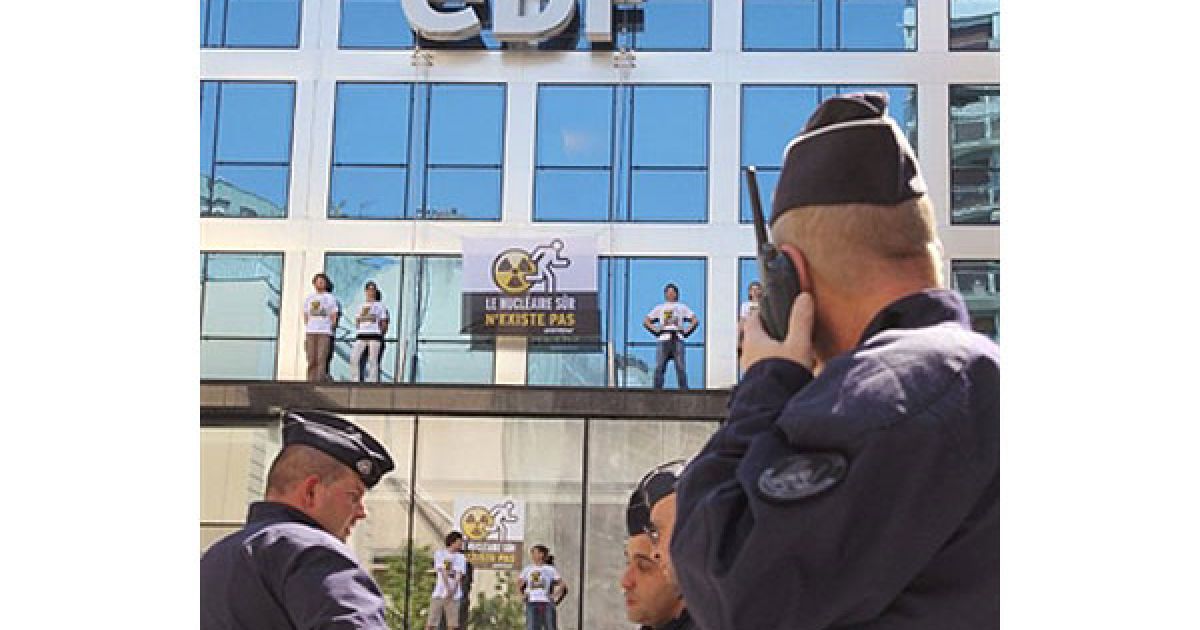 Франція, Париж. Члени руху "Грінпіс" тримають плакати "Безпечної ядерної енергії не існує" під час акції протесту, доки поліцейські спостерігають за ними. / © AFP
