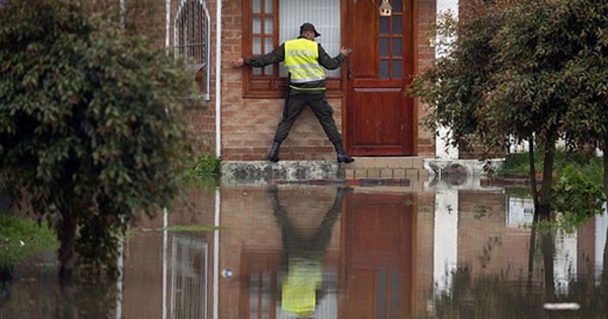 Колумбія, Чіа. Колумбійський поліцейський перебирається через вулицю міста, затоплену в результаті сильних дощів на півночі країни. / © AFP