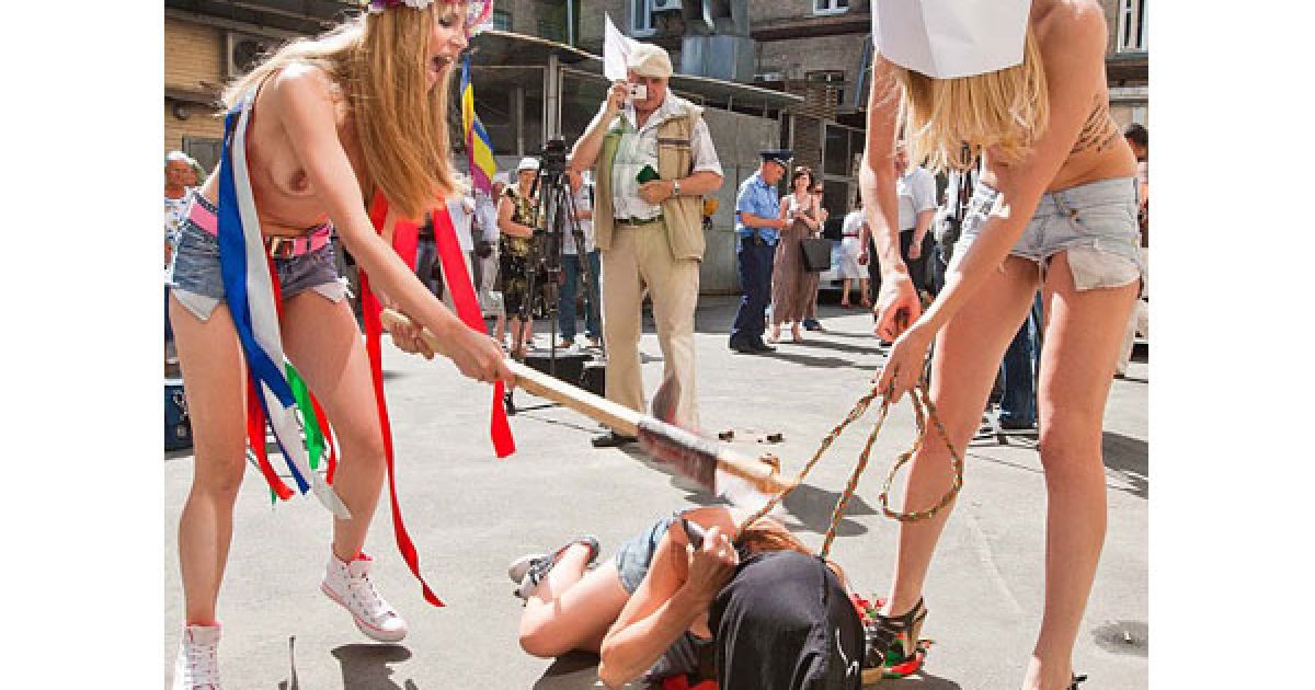 Оголені дівчата з руху FEMEN у ковпаку ката та з макетом сокири в руках почали імітувати страту з криками "Забій кролятини".