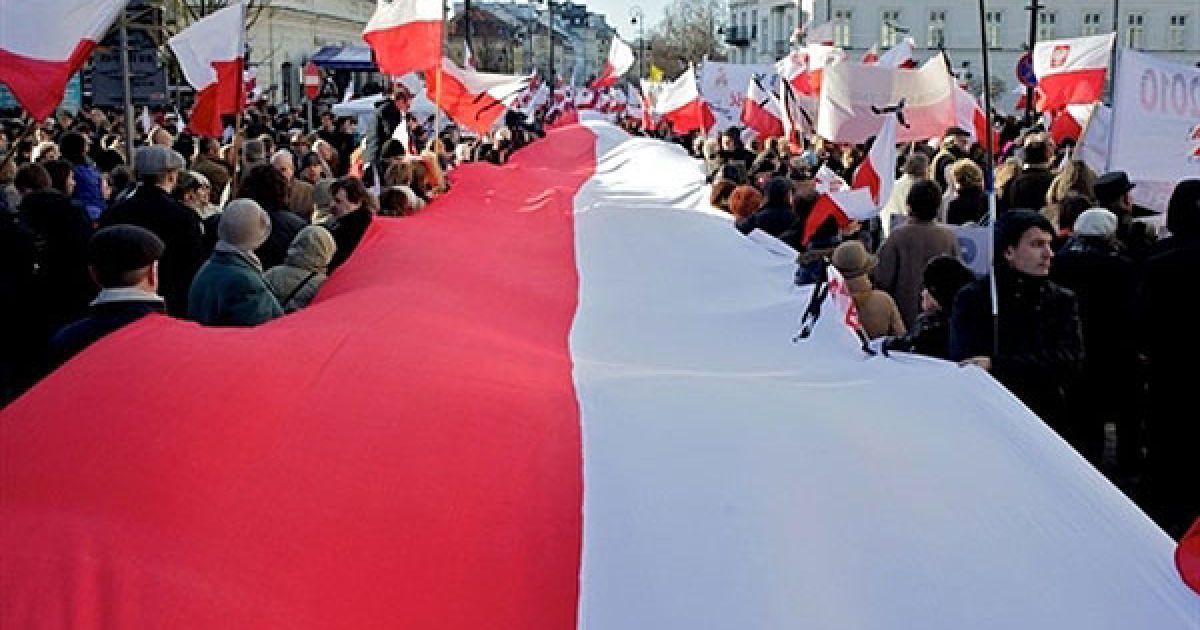 Польща, Варшава. Люди тримають гігантський польський прапор під час поминальної служби в пам&#039;ять про загиблих в авіакатастрофі під Смоленськом, яку провели перед президентським палацем у Варшаві. / © AFP