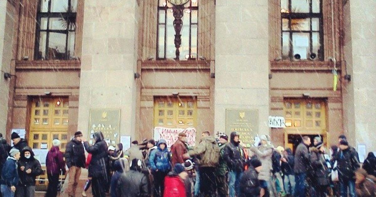 Люди танцюють під снігом біля будівлі КМДА.