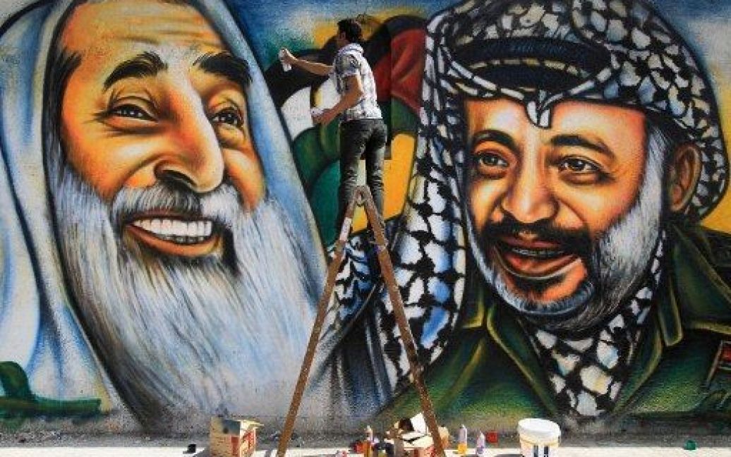 Місто Газа. Палестинський художник Мохаммед аль-Даїрі створив граффіті із зображенням покійного палестинського лідера Ясіра Арафата та покійного лідера ХАМАС, шейха Ахмеда Ясіна у місті Газа. / © AFP