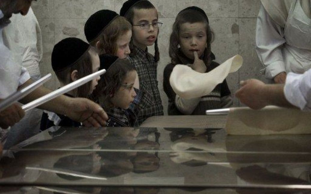 Єрусалим. Діти дивляться як ультра-ортодоксальні євреї замішують тісто для випічки Маци в Єрусалимі. Релігійні євреї в усьому світі їдять мацу протягом восьми днів свята Песах (Великдень), яке починається 6 квітня. / © AFP