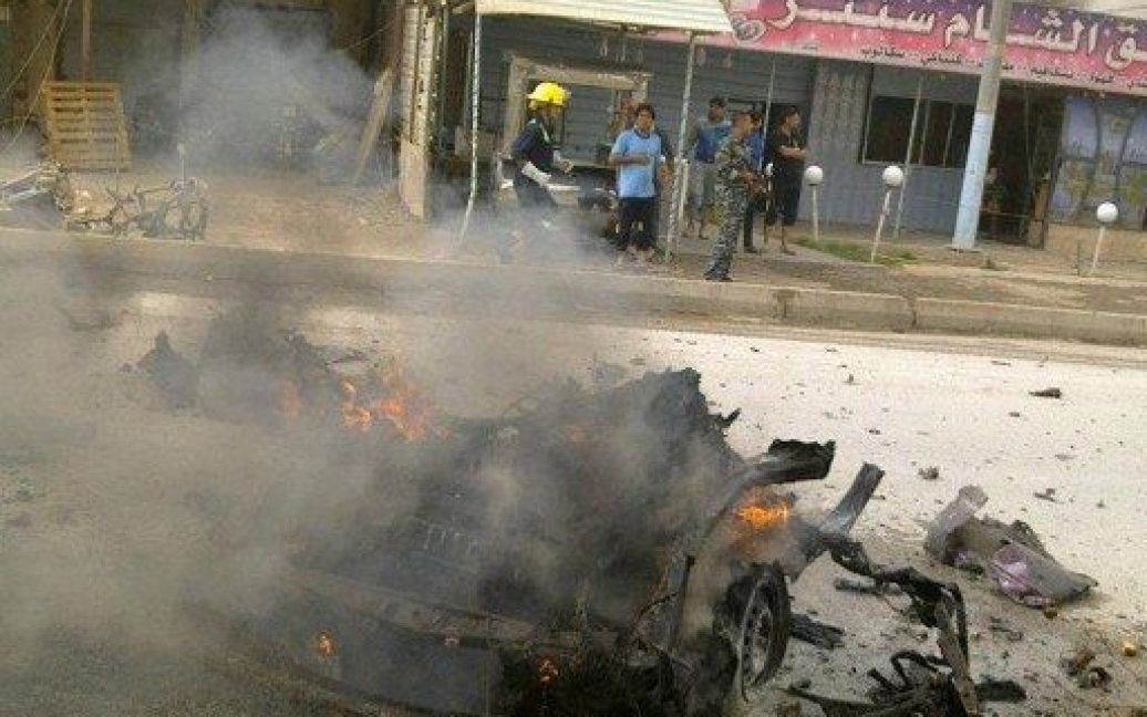Ірак, Рамаді. Люди дивляться, як догорає автомобіль, який вибухнув в іракському місті Рамаді в західній провінції Анбар. / © AFP