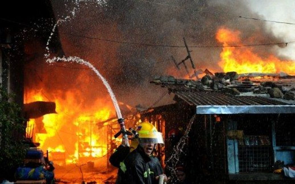 Філіппіни, Маніла. Пожежні намагаються загасити вогонь, який охопив район нелегальних поселенців у Манілі. В результаті пожежі близько 150 сімей залишились без будинків. / © AFP