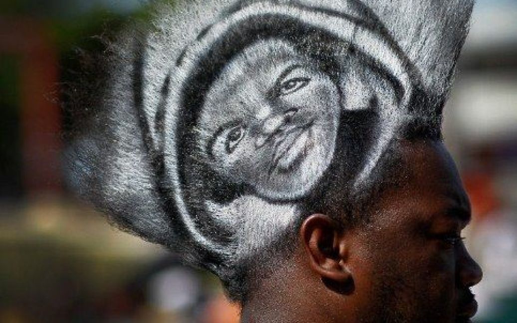 США, Майамі, штат Флорида. Чоловік з портретом Трейвона Мартіна на ірокезі бере участь у мітингу на його честь у Майамі. Мартін був убитий членом громадського патруля у містечку Twin Lakes. / © AFP