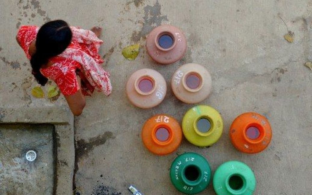 Індія, Бангалор. Жінка набирає питну воду у пластикові горщики з громадського крану в Бангалорі. Шість найбільших міст Індії: Мумбаї, Делі, Калькутта, Бангалор, Ченнай і Хайдарабад, - найбільше за інші міста потерпають від нестачі питної води. / © AFP
