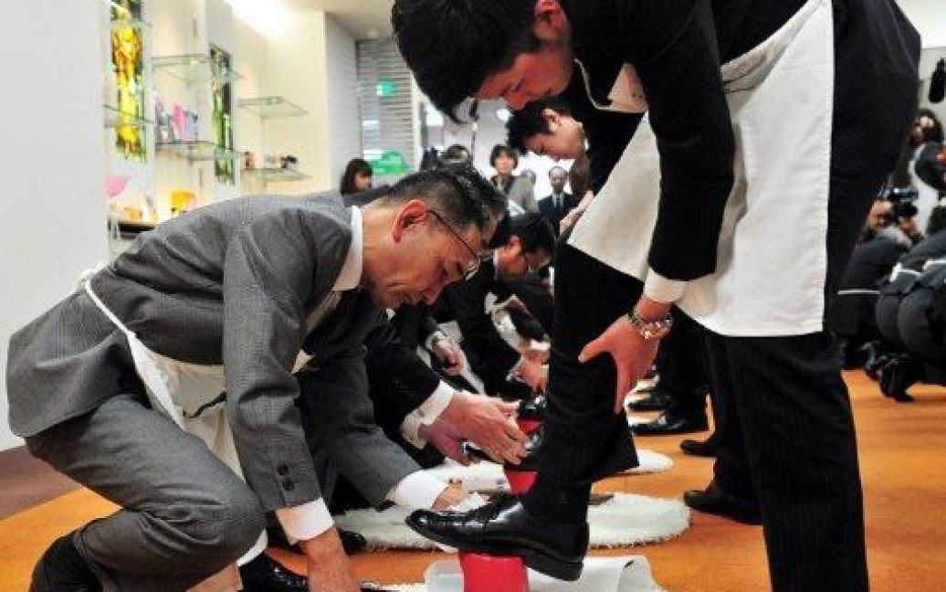 Японія, Токіо. Топ-менеджер компанії з виробництва крему для взуття полірує черевики нового співробітника під час церемонії у штаб-квартирі компанії. Новим співробітникам надали майстер-клас з чищення взуття. / © AFP