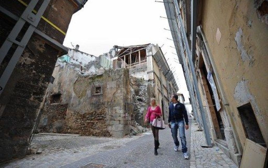 Італія, Аквіла. Люди йдуть вулицями у "червоній зоні" міста Аквіла, закритій для громадськості. Історичний район Аквіли був три роки тому зруйнований потужним землетрусом. / © AFP