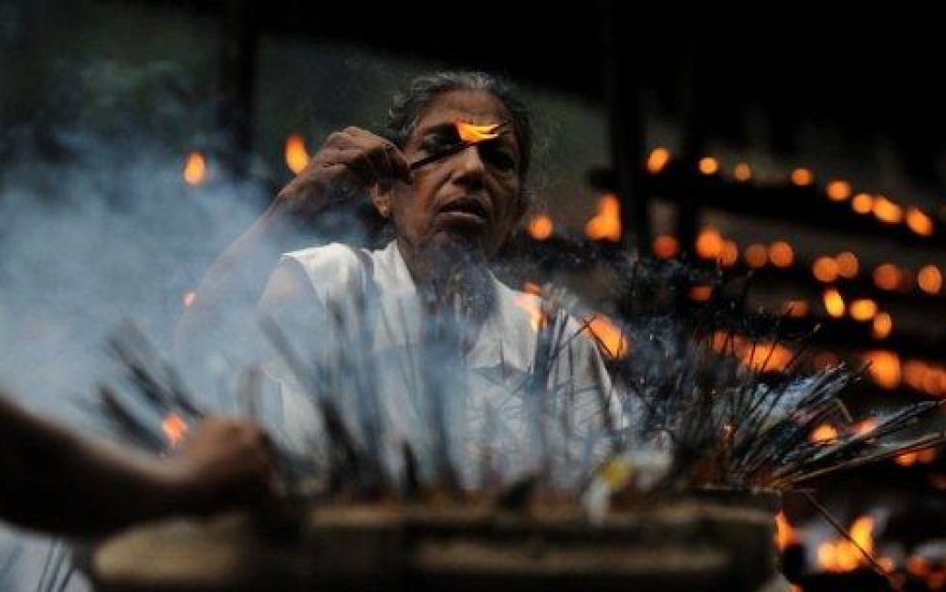 Шрі-Ланка, Коломбо. Буддійська віддана запалює ароматичні палички під час святкової молитви у храмі Келані Келані. / © AFP