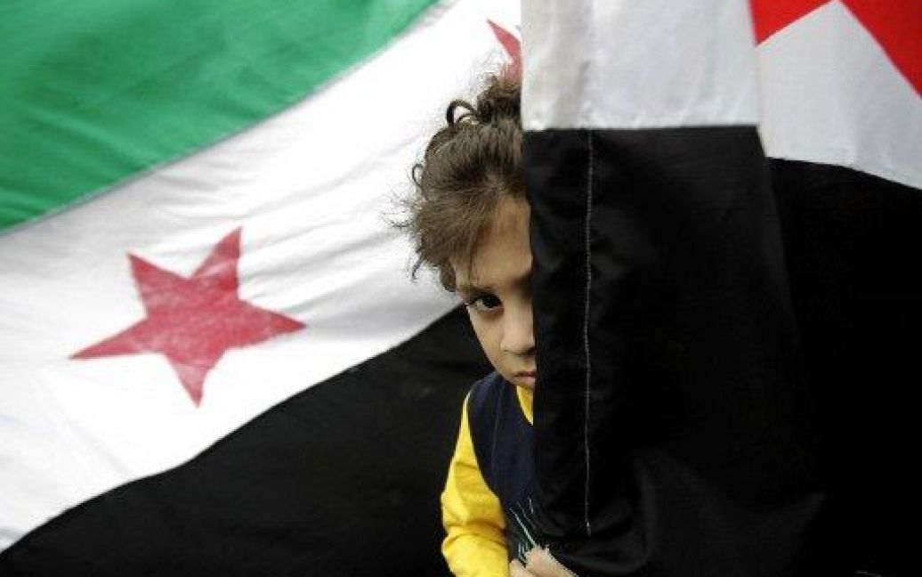 Ліван, Бейрут. Дитина ховається за сирійськими прапорами під час демонстрації прихильників руху "Джамаа Ісламія" проти режиму президента Башара аль-Асада. / © AFP