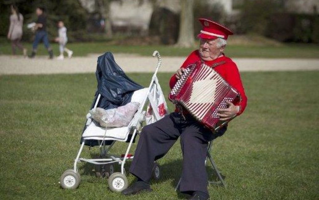 Франція, Трілпорт. Дідусь грає на акордеоні на площі у весняний теплий день. / © AFP