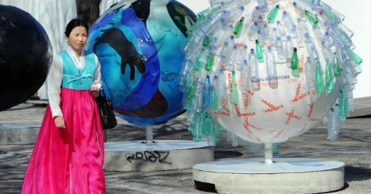 Франція, Марсель. Жінка проходить повз прикрашену пластиковими пляшками води кулю, яку встановили у Марселі з нагоди проведення 6-го Всесвітнього водного форуму. / © AFP