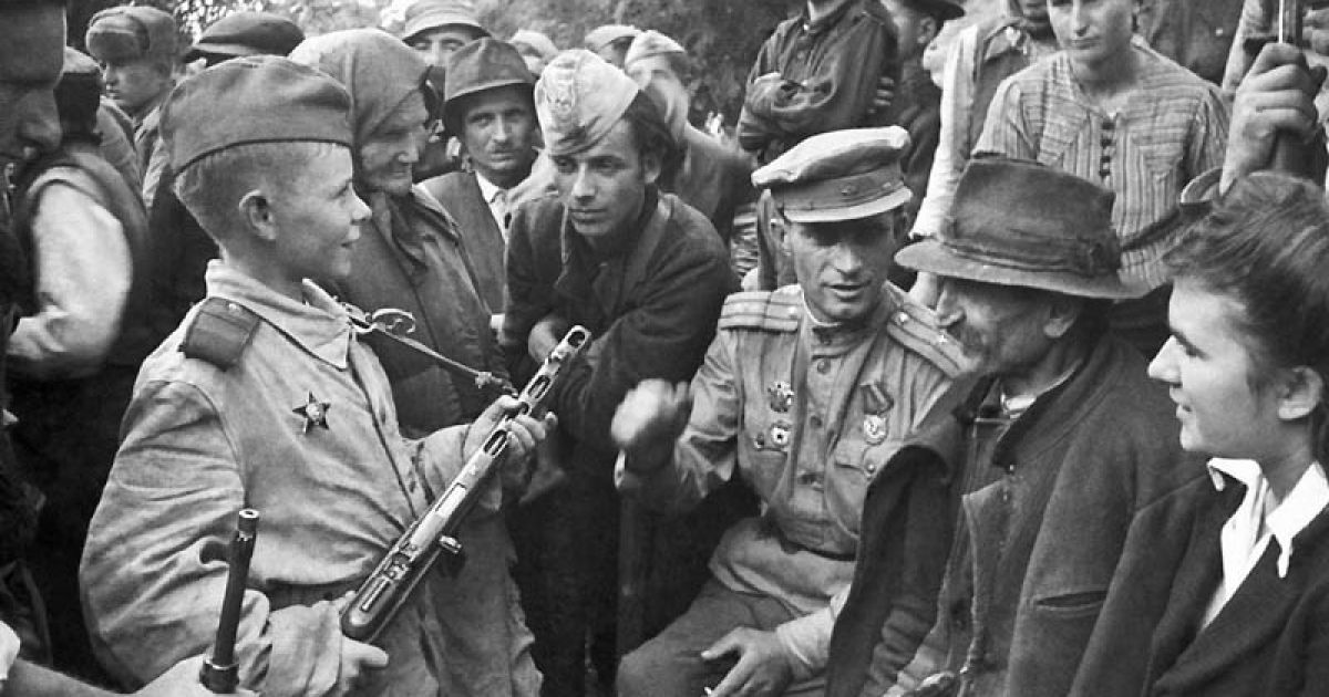 Командир стрілецького батальйону майор В.Романенко розповідає югославським партизанам і жителям села Старчево (в районі Белграда) про бойові справи юного розвідника єфрейтора Віті Жайворонка. Югославія, 1944 / © bigpicture.ru