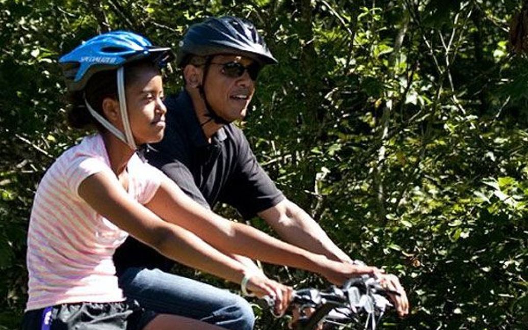 США, штат Массачусетс. Президент США Барак Обама з дочкою Малією катаються на велосипедах під час відпочинку у державному лісовому заповіднику Західній Тісбері в штаті Массачусетс. / © AFP