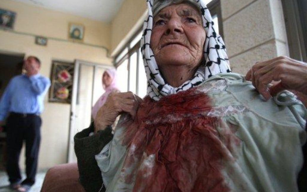Міхмасу. 80-річна палестинка Айша Халіл показує свою сукню з плямами крові. Літня жінка під час збирання врожаю з оливкових дерев в селі на Західному березі потрапила під обстріл каменням, який влаштували ізраїльські поселенці з сусіднього форпосту Мігроні. / © AFP