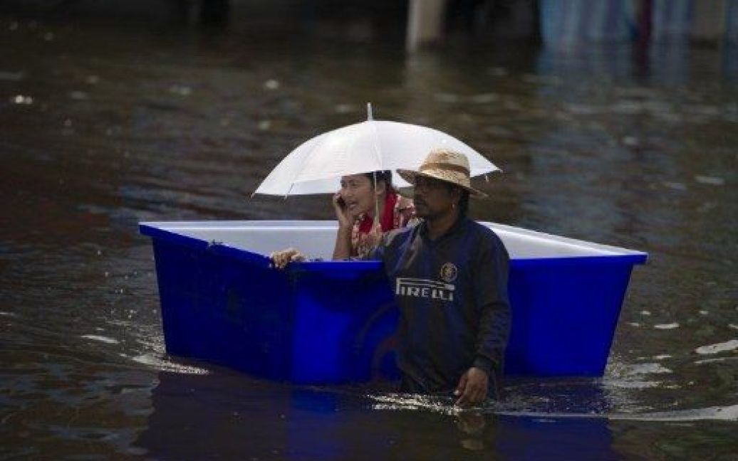 Таїланд, Патхумтхані. Жінка та чоловік пробираються через затоплену вулицю у передмісті Бангкока. Країна потерпає від повеней, існує загроза підтоплення столиці Таїланду. / © AFP