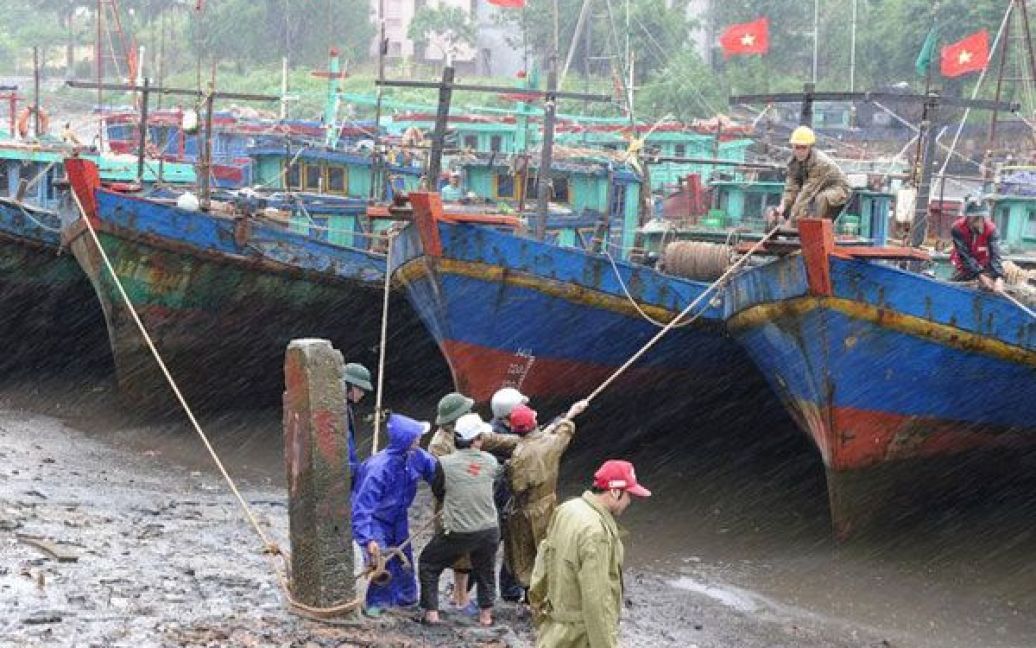 В&#039;єтнам, Тай Туї. Добровольці "Червоного Хреста" та рибалки закріплюють рибальські човни перед наближенням потужного тайфуну Несат до північно-східної провінції Тай Бін. Тисячі людей у В&#039;єтнамі готуються до удару стихії та заздалегідь шукають притулок. / © AFP