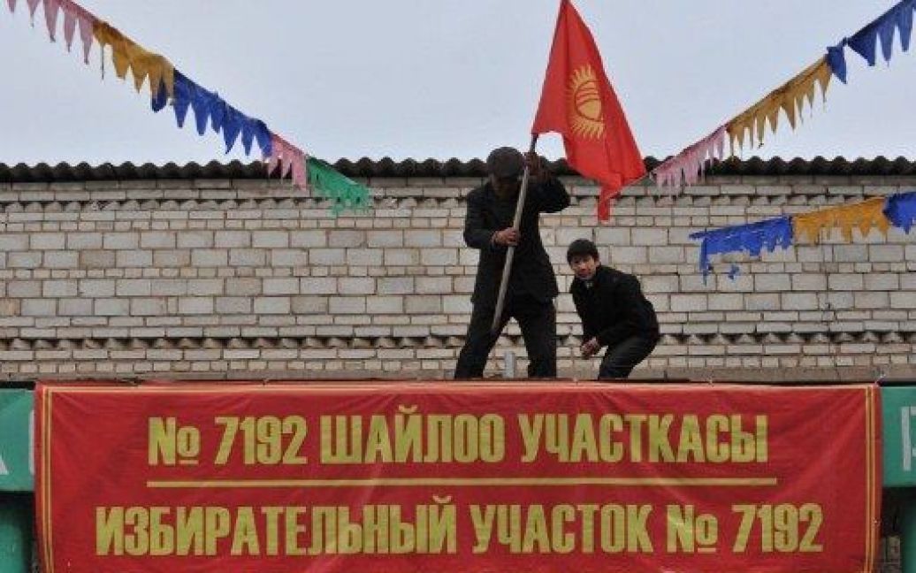 Киргизстан, Беш-Кунгей. Працівники встановлюють національний прапор Киргизії на даху місцевої виборчої дільниці в селищі Беш-Кунгей поблизу Бішкека. Країна готується до майбутніх президентських виборів, які призначені на 30 жовтня. / © AFP