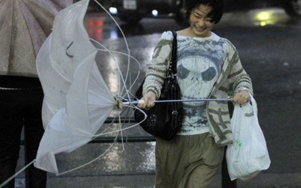 Японія, Токіо. Жінка несе зламану парасольку під сильним вітром. Тайфун Роке обрушився на Токіо, вже загинули щонайменше чотири людини. / © AFP