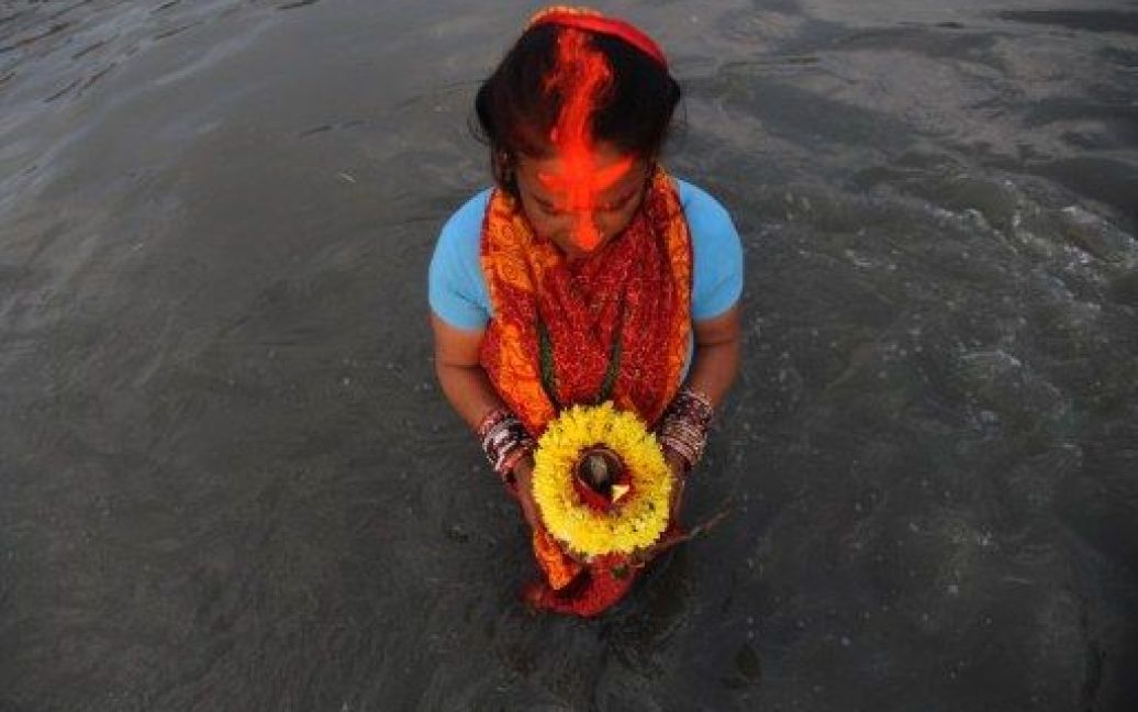 Непал, Катманду. Непальська жінка поклоняється сонцю в річці Багматі під час святкування фестивалю Чіта, присвяченого Богу Сонця. / © AFP