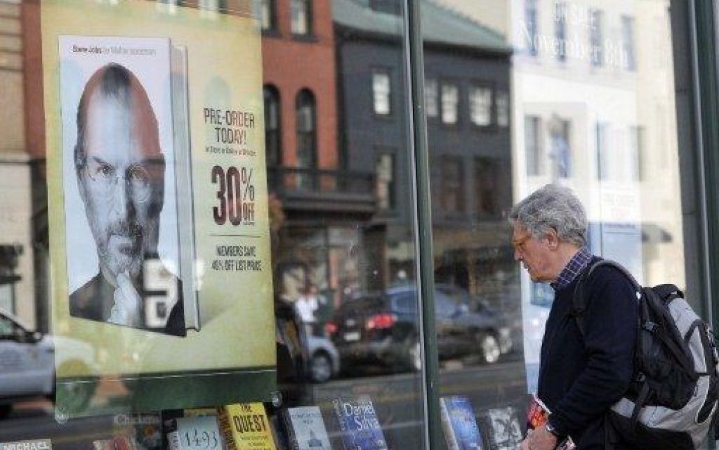 США, Вашингтон. Людина роздивляється плакат із рекламою біографічної книги засновника компанії Apple Стіва Джобса, виставлений на вітрині книжкового магазина в Джорджтауні у Вашингтоні. / © AFP
