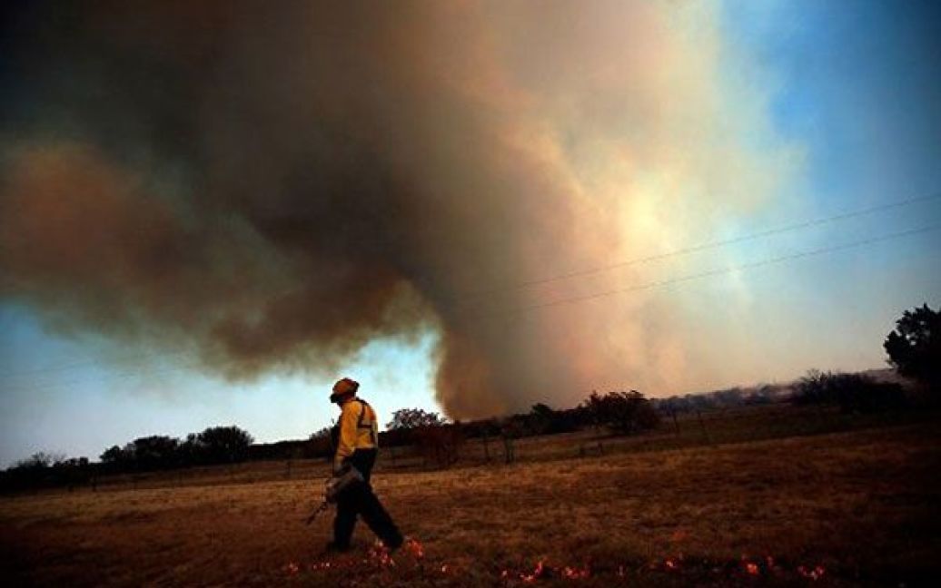 США, Графорд, штат Техас. Пожежний-волонтер бере участь у гасінні лісової пожежі в штаті Техас. Більше 45 будинків у цьому районі згоріли, доки лісові пожежі поширювалися через Техас і Оклахому. / © AFP