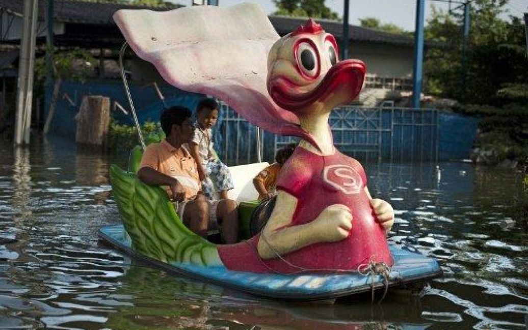 Таїланд, Банг Буа Тхонг. Місцеві жителі на човні пливуть затопленими вулицями у передмісті Бангкока. Столиця Таїланду була оголошена зоною стихійного лиха після прориву дамби на річці Чао Прайя і виникнення загрози затоплення міста. Таїланд потерпає від найсильнішої за останні 50 років повені. / © AFP