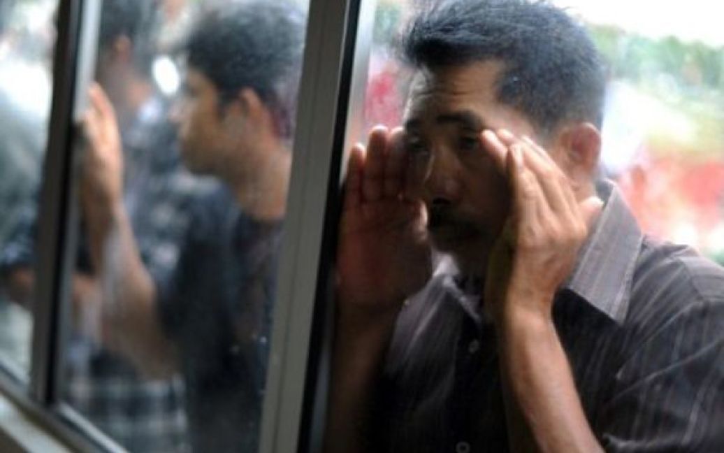 Малайзія, Куала-Лумпур. Іноземні робітники заглядають до вікна будинку прикордонної служби, де вони мають пройти біометричний контроль. Першого серпня Малайзія оголосила амністію для майже 2 мільйонів нелегальних робітників. / © AFP