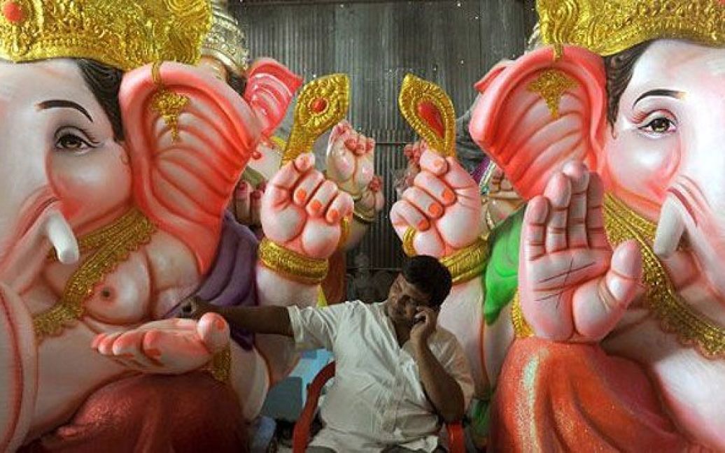 Індія, Бангалор. Індійський художник сидить поруч з фігурами індуїстського бога Ганеша (із головою слона) на ринку в Бангалорі. Індія готується до святкування фестивалю "Ганеш Чатуртхі", популярного релігійного свята, яке буде відзначатися з 1 по 11 вересня. / © AFP