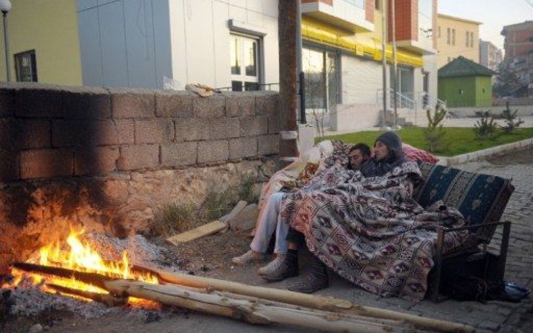 Туреччина, Еркіс. Люди сплять на дивані перед багаттям посеред вулиці міста, яке постраждало в результаті сильного землетрусу в провінції Ван на сході Туреччини. / © AFP