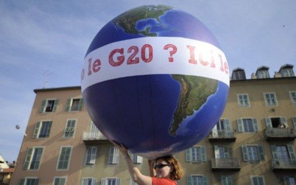 Франція, Канни. Жінка тримає повітряну кулю у формі Землі під час демонстрації напередодні проведення саміту G20 в Каннах. Тисячі "анти-капіталістів" провели марш протесту проти "корпоративної жадібності". / © AFP