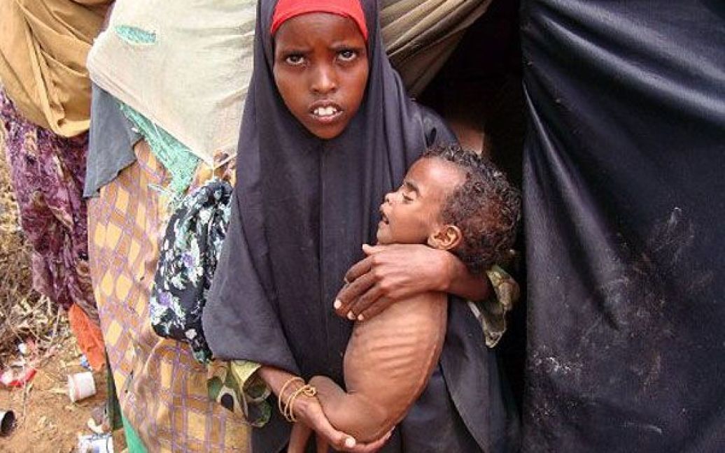 Сомалі, Могадішо. Внутрішньо переміщена молода жінка несе свою дитину до медичного центру в таборі для переміщених у Могадішо. Делегація від саудівської королівської родини на чолі з князем Алвалідом бен Талалом, одним з найбагатших людей королівства, прибула до табору біженців, щоб оцінити масштаби необхідної допомоги. / © AFP