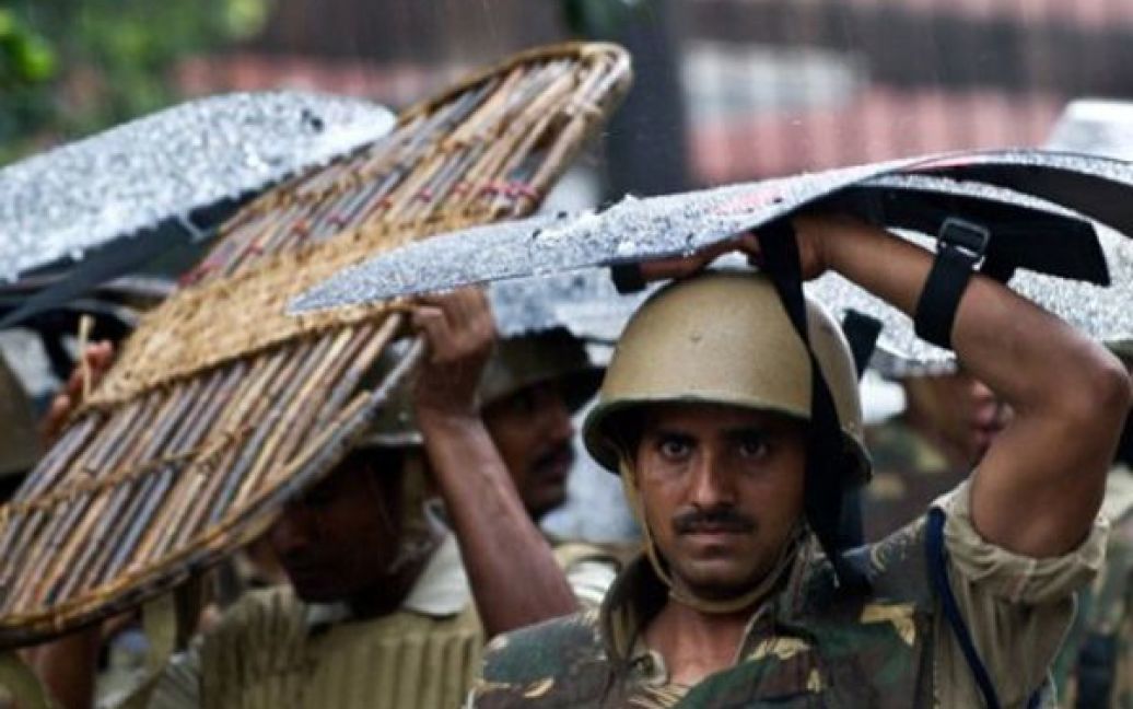 Індія, Делі. Солдати спецназу вкриваються своїми щитами від дощу під час мітингу опозиції під стінами парламенту. Обурення опозиції викликала бездіяльність уряду та парламенту у боротьбі з корупцією. / © AFP