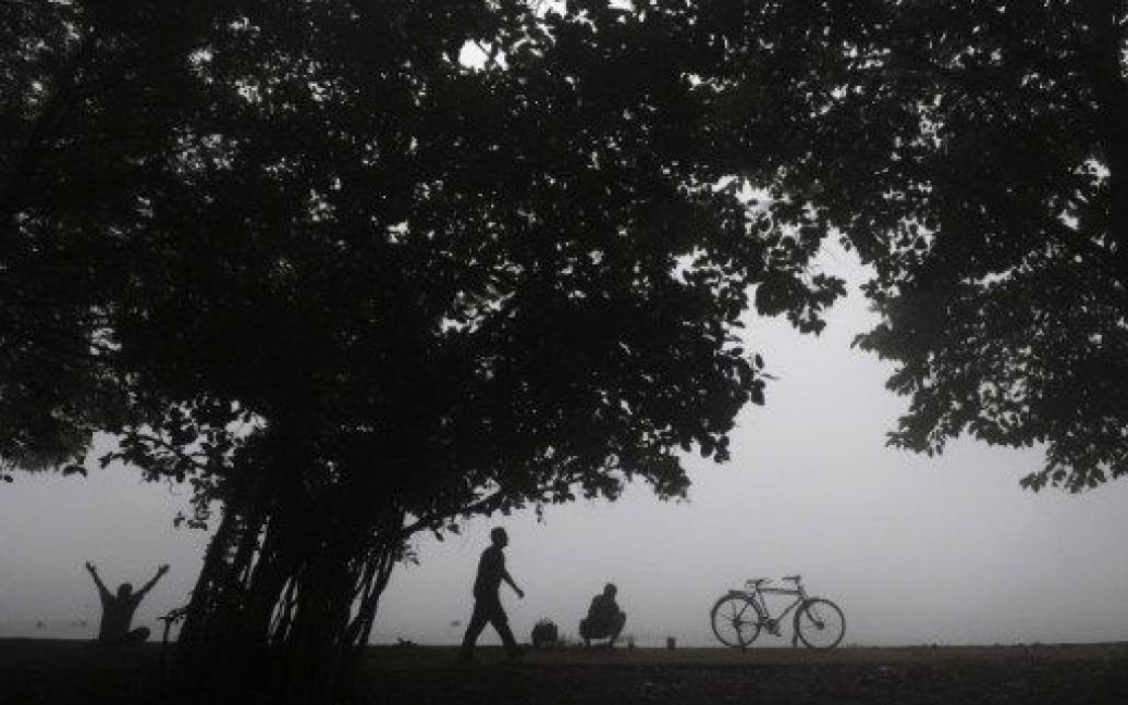 Індія, Калькутта. Люди роблять ранкову зарядку на березі озера, вкритому густим туманом. / © AFP