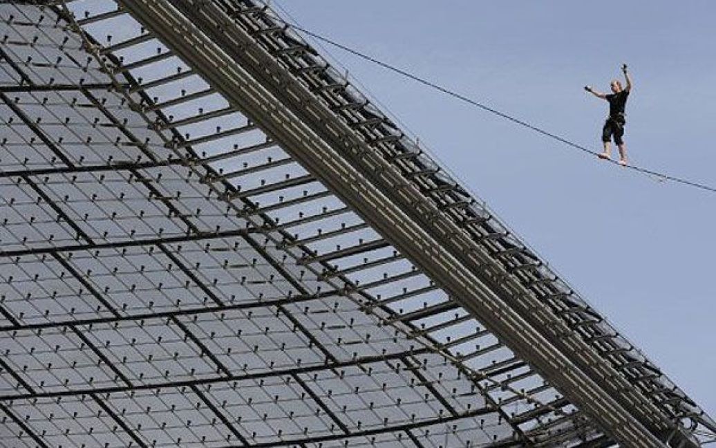 Німеччина, Мюнхен. Відвідувач фестиваль на відкритому повітрі балансує на мотузці над дахом Олімпійського стадіону в Мюнхені. / © AFP