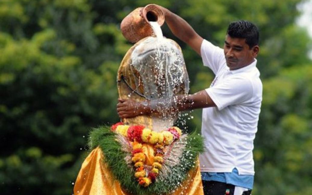 Непал, Катманду. Чоловік поливає золоту статую бога Нага молоком на честь початку фестивалю Наг-Панчамі. Протягом цього фестивалю, що проводиться у сезон мусонів, непальці віддаються шану зміям. / © AFP