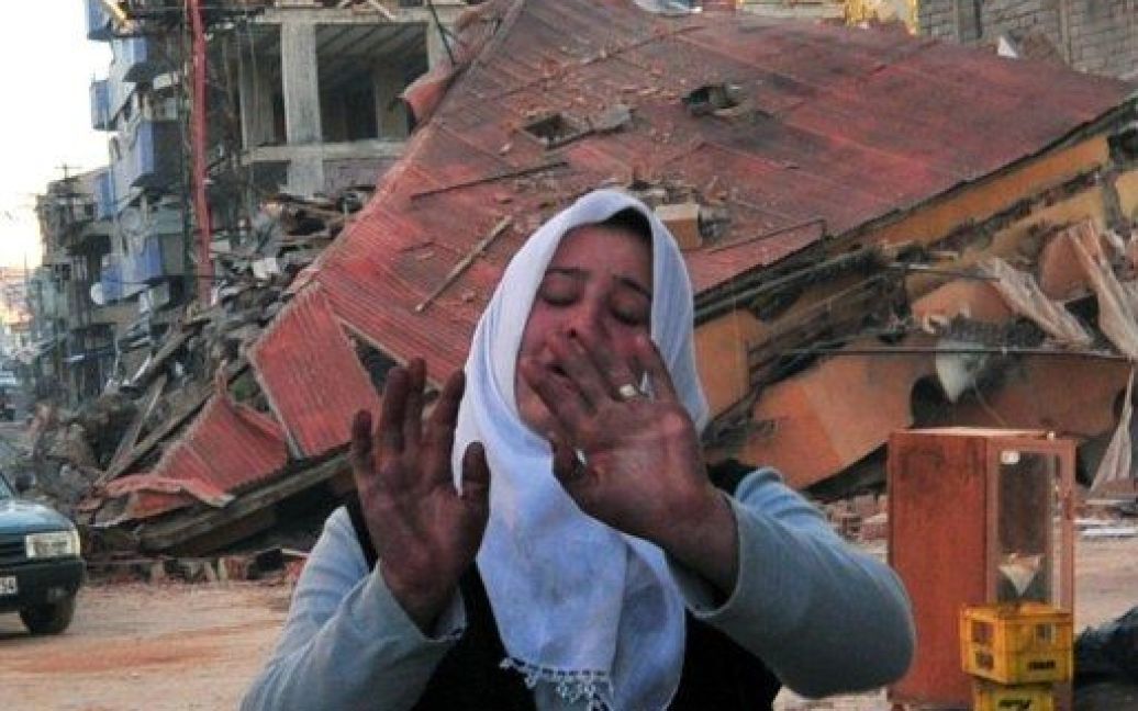 Туреччина, Еркіс. Жінка плаче перед своїм будинком, який обвалився в результаті потужного землетрусу в провінції Ван на сході Туреччини. Рятувальники продовжують пошуки під завалами тих, хто вижив після сильного землетрусу, загинули щонайменше 270 осіб. / © AFP