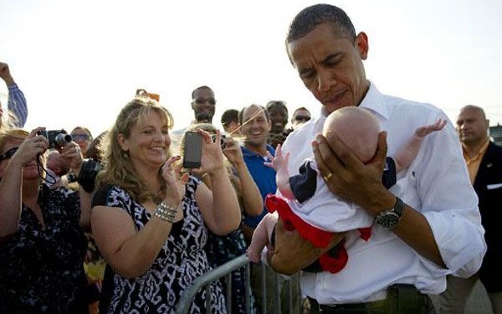 США, Кейп-Код. Президент США Барак Обама тримає дитину під час візиту до станції берегової охорони Кейп-Код у штаті Массачусетс. Адміністрація Обами заявила, що вона відкладе депортацію незаконних іммігрантів і надасть їм можливість подати заяву на дозвіл на роботу. / © AFP