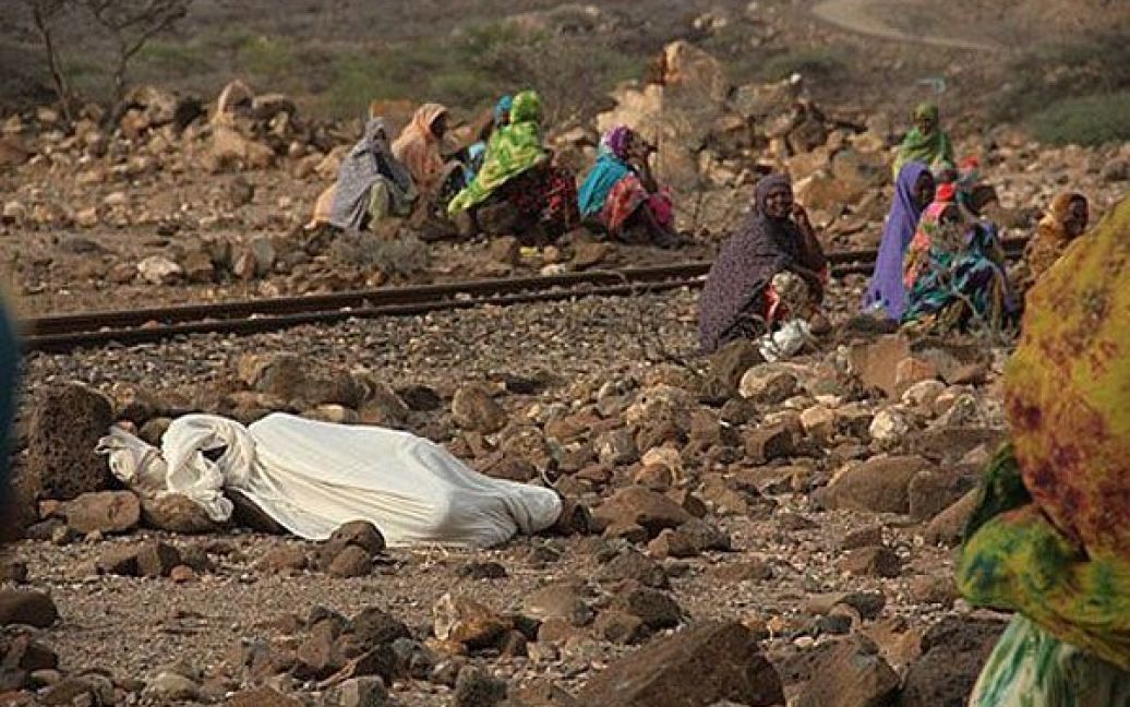 Джибуті, Гарабтісан. Жінки сидять поруч із тілом, вкритим тканиною. Мешканці північних районів Джибуті сильно постраждали від посухи та голоду. За даними ООН, 146 тисяч людей в Джибуті потерпають від найсильнішої за кілька десятиліть посухи, яка також вразила Ефіопію, Кенію, Уганду і Сомалі. / © AFP