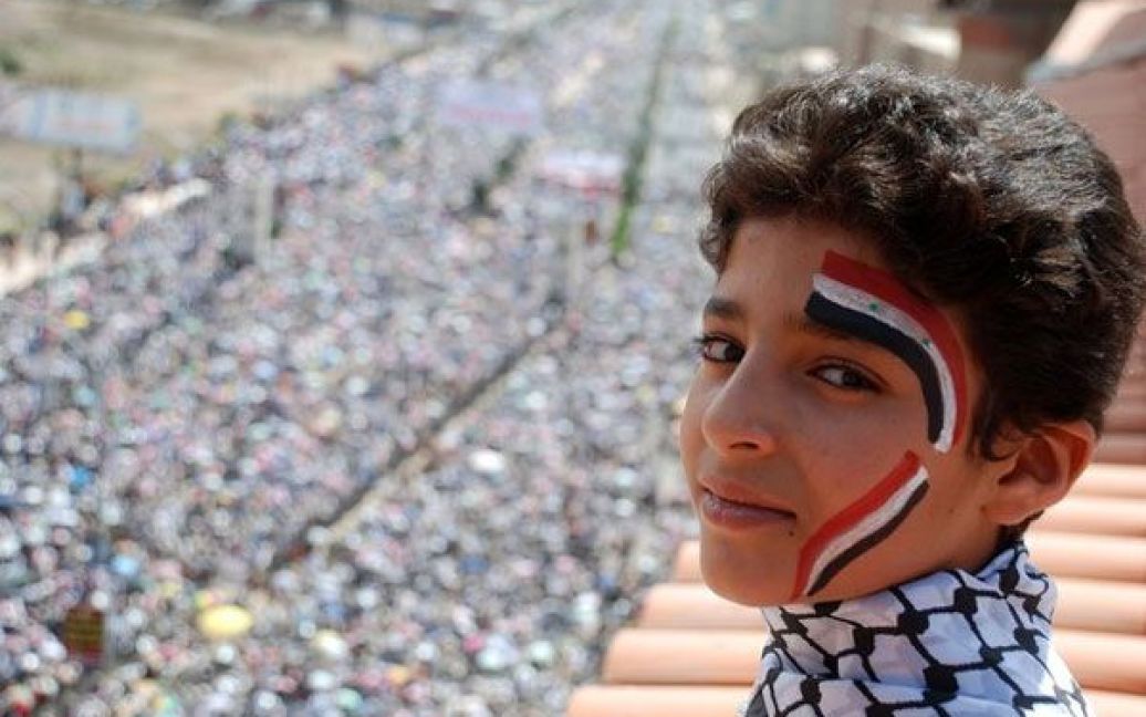 Ємен, Сана. Єменський хлопчик із обличчям, пофарбованим у кольори єменського та сирійського прапорів, бере участь у масовій акції протесту після п&#039;ятничної молитви в Сані. В Ємені тривають заклики до президента Алі Абдалли Салеха піти у відставку та антиурядові протести. / © AFP