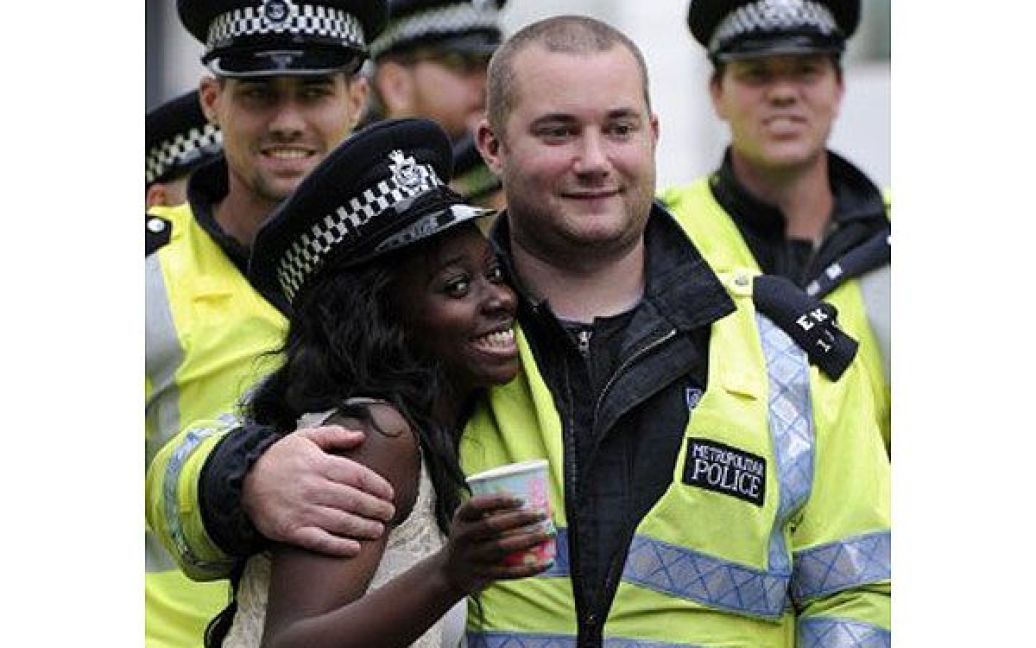 Великобританія, Лондон. Жінка обнімається з поліцейським та посміхається під час участі у дводенному, найбільшому в Європі, вуличному карнавалі "Ноттінг Хілл" у Лондоні. / © AFP