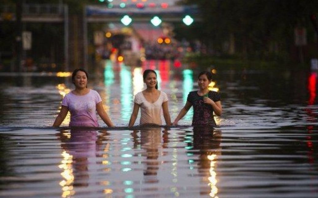 Таїланд, Бангкок. Місцеві жителі йдуть затопленою вулицею в Бангкоку. Повінь затопила більшу частину столиці Таїланду, захисні бар&#039;єри уздовж головної річки в Бангкоку не допомогли запобігти катастрофічному підтопленню. / © AFP