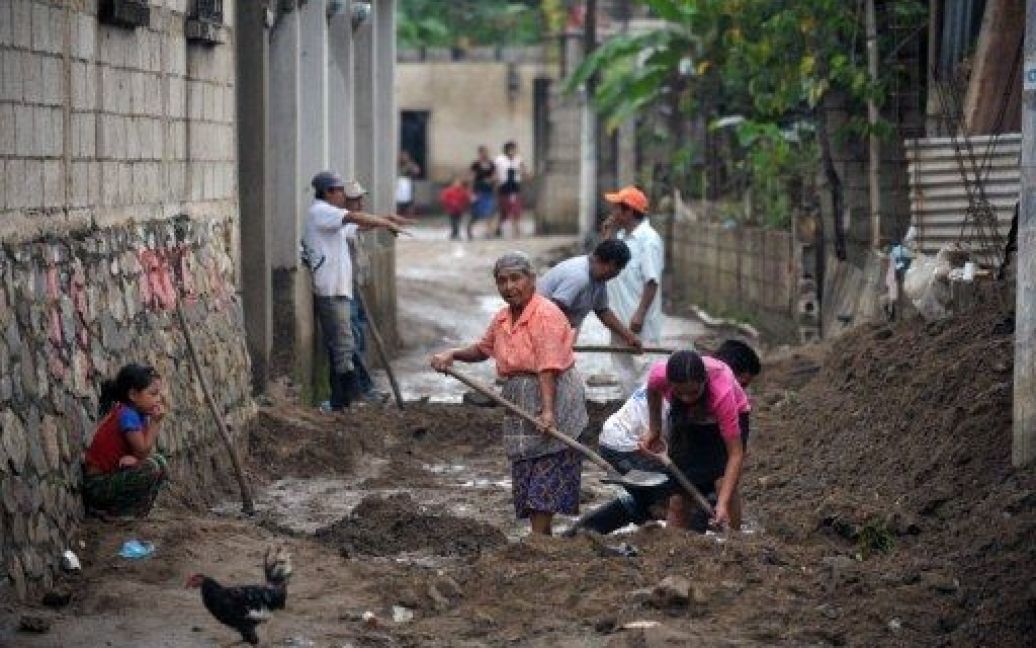 Гватемала, Сан-Педро. Мешканці прибирають бруд зі своїх будинків в місті Ель-Аквате, яке постраждало від стихійного лиха. Гватемальський президент Альваро Колом оголосив "надзвичайний стан" через проливні дощі, які обрушилися на країну. В результаті удару стихії, 29 осіб загинули, більше 150 тисяч постраждали. / © AFP